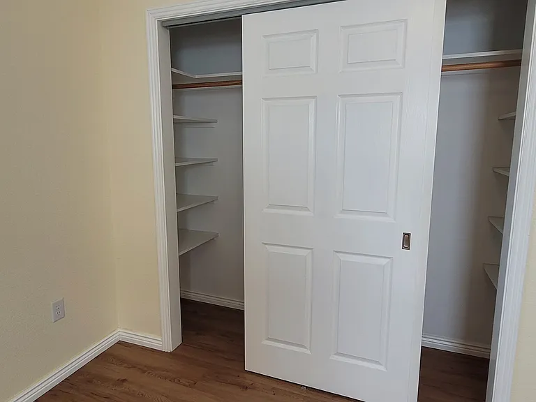 Large closet in Master Bedroom with shelves on either end and 2 sliding doors.