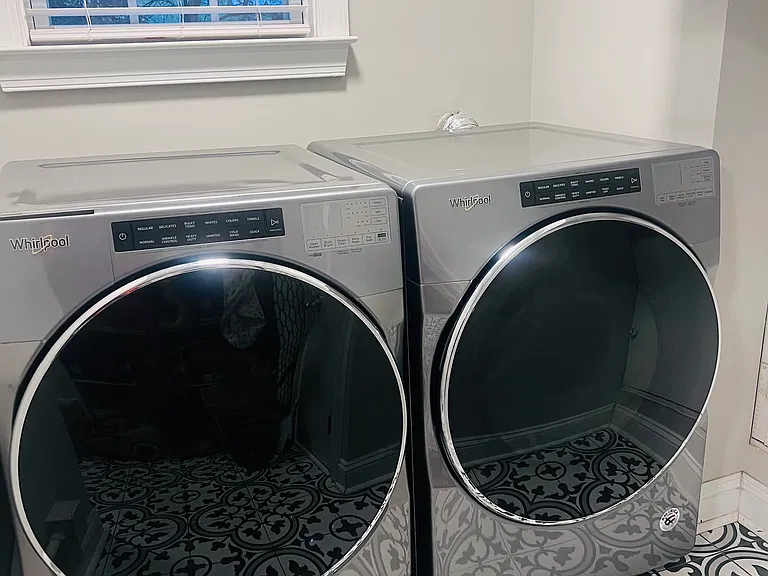 Full size washer and dryer in dedicated laundry room with storage and shelves.