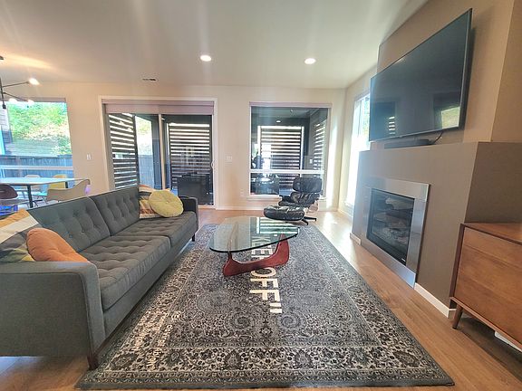 Living room with sliding door to outdoor covered deck featuring outdoor fireplace