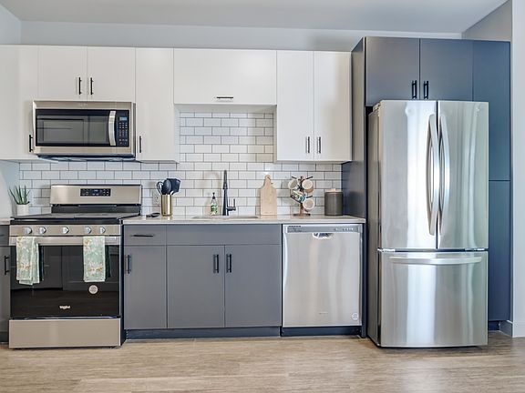 Modern kitchens outfitted with stainless steel appliances and quartz countertops with tile backsplashes.