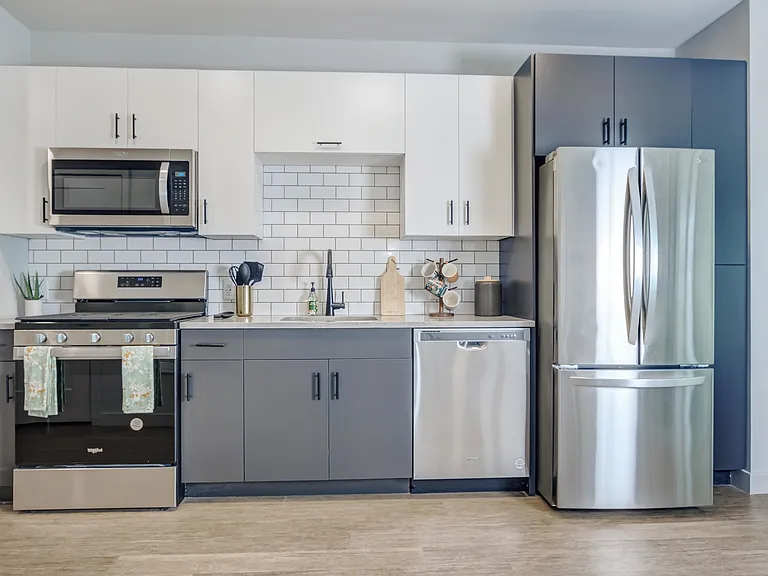 Modern kitchens outfitted with stainless steel appliances and quartz countertops with tile backsplashes.