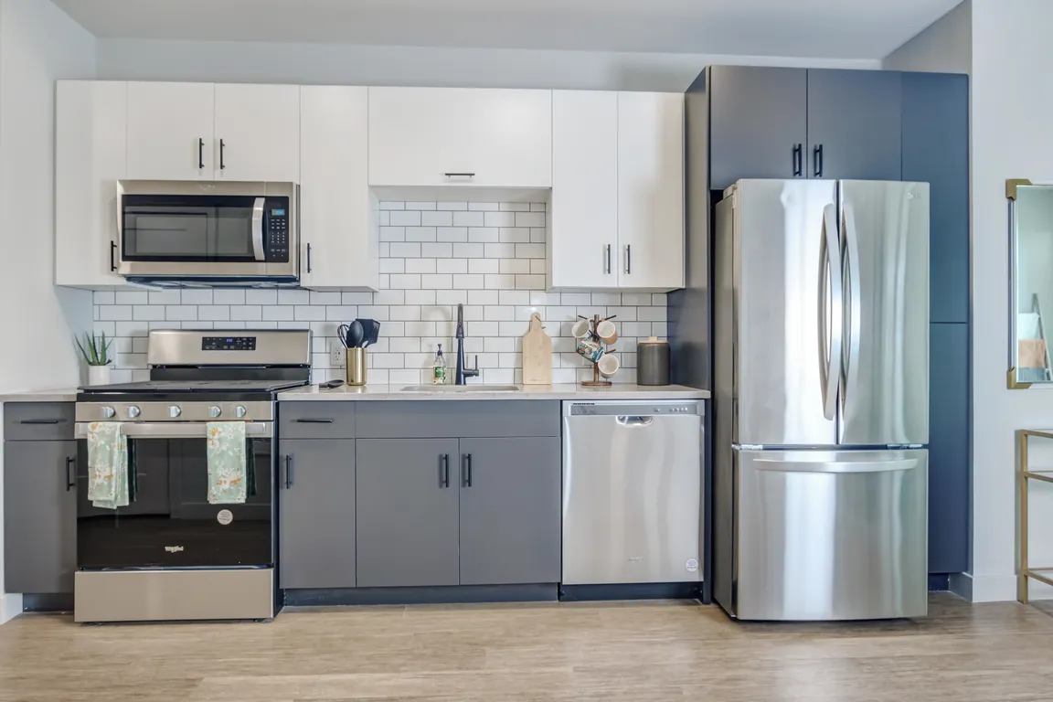 Modern kitchens outfitted with stainless steel appliances and quartz countertops with tile backsplashes.