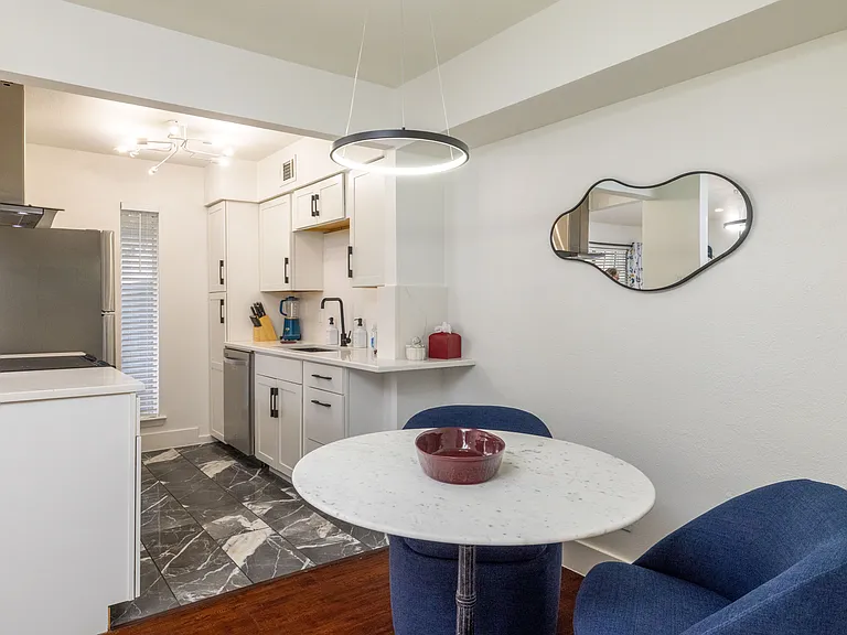 A cozy dining nook with plush navy chairs and a modern round table. Ideal for meals, planning your day, or relaxing with good company.