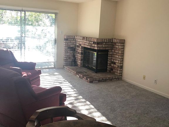Living room with fireplace, ceiling fan is over table for dining area