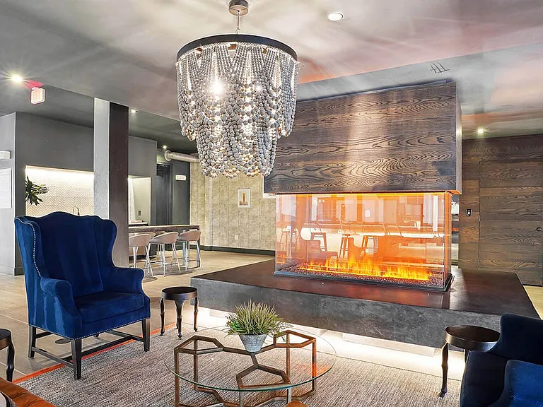 Entertainment lounge with fireplace, plush seating, and elegant chandelier.