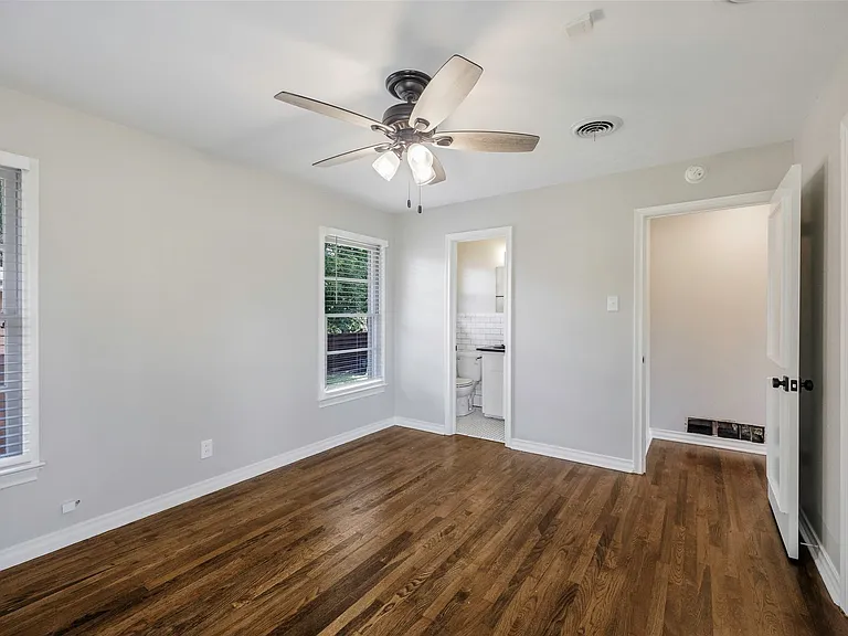 Master bedroom with ceiling fan, a healthy amount of sunlight, and dark wood-type flooring