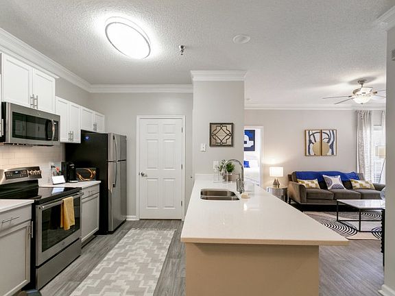 Interior photo of the kitchen with stainless steel appliances, white subway tile, blue cabinets and laundry room