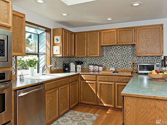 Check out this spacious kitchen with newer built-in microwave, oven and dishwasher! The cabinets include many pull-out shelves which make it easier to reach everything. This space is light and bright with a huge skylight overhead and a garden window that over looks the front yard and planter in the cup-de-sac.