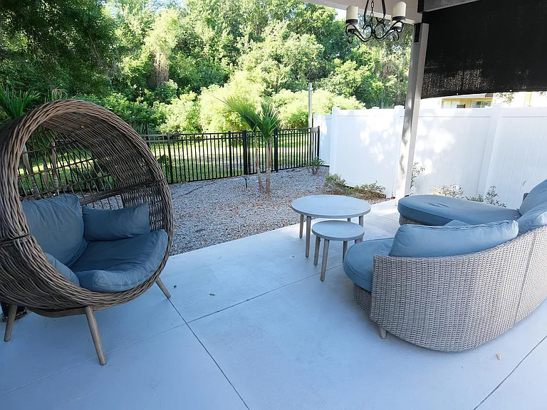 Charming outdoor patio featuring cozy wicker furniture, lush green surroundings, and serene garden views.
