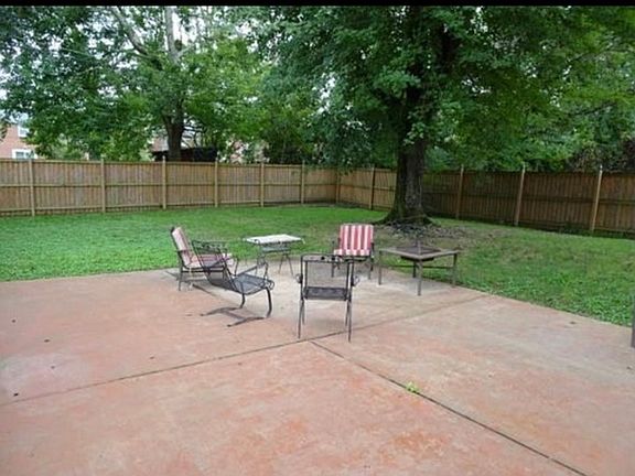Cement patio in large fenced in backyard.