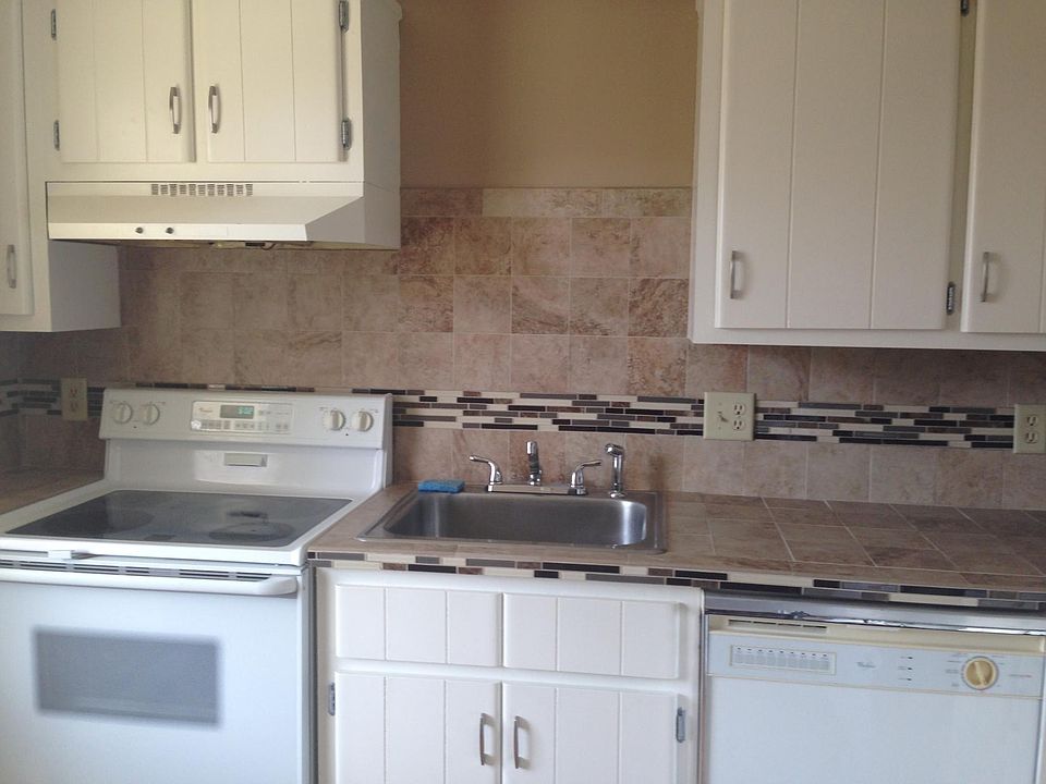 Kitchen with glass top electric range, dishwasher, refrigerator, tiled counter top and backsplash