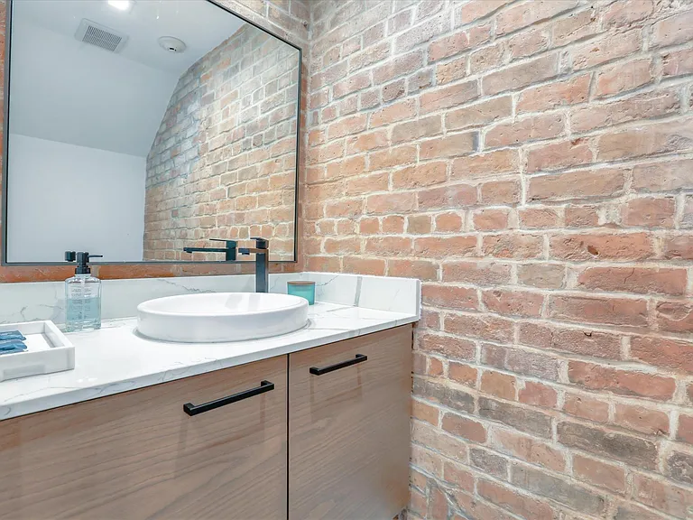 The bathroom on the first floor also features exposed brick and high-end finishes.