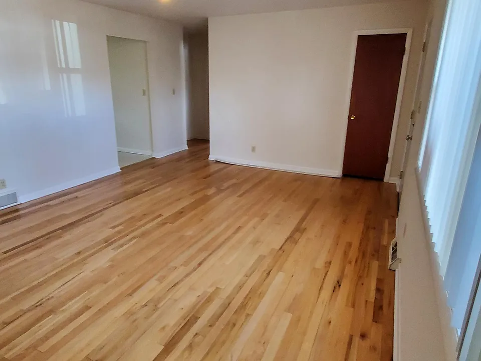 Living room, looking towards bedrooms. Kitchen is on the left. Front door is closed and narrow dark door is a coat closet.