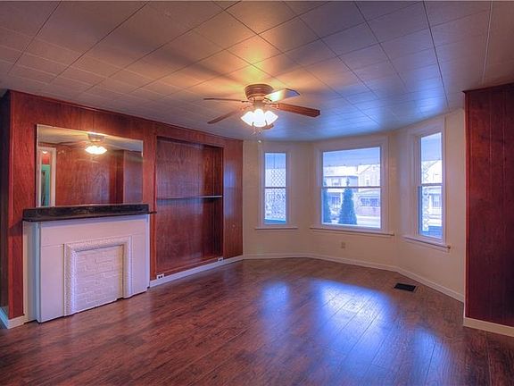 The Living Room features a curved wall of windows, warm-tone laminate flooring and a decorative fireplace.