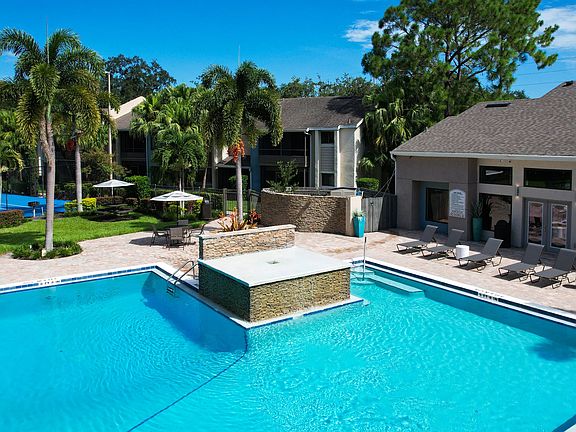 Unwind in style at the Harper Grand pool, featuring lush palm trees, comfortable lounge chairs, and a serene water feature for ultimate relaxation.