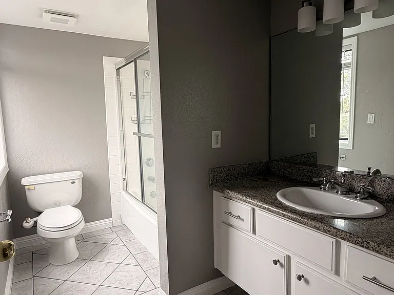 Main bathroom with vanity, tile flooring, toilet, and tub/shower area.