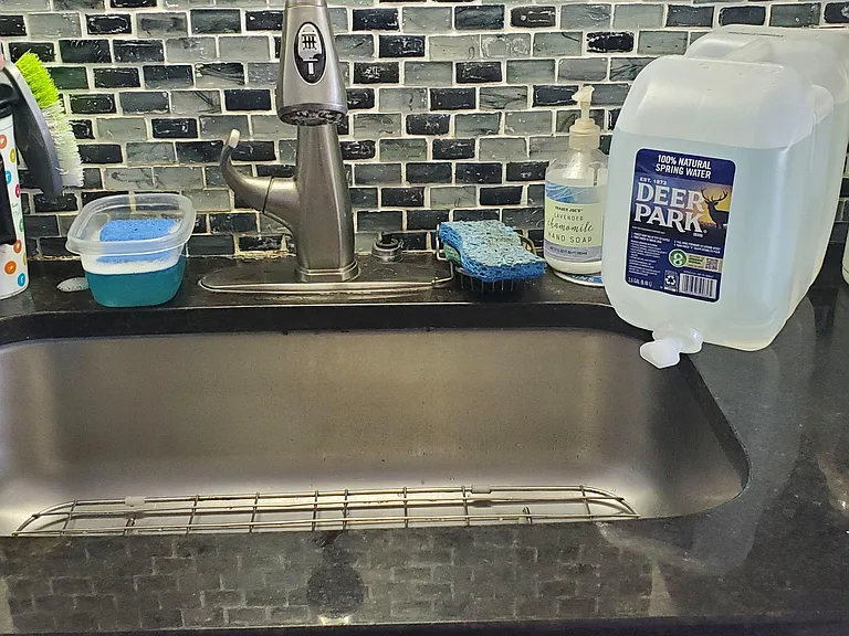 Functional kitchen sink area with a deep basin, gooseneck faucet, and tile backsplash for easy everyday cleanup.