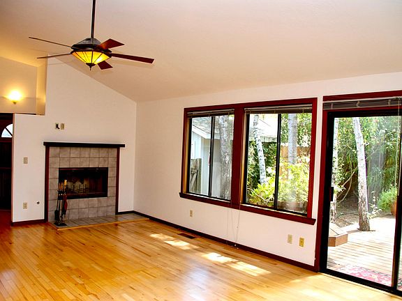 Great room facing towards entry way which can be slightly seen on left, large redwood deck is on right with birch tree growing through it.