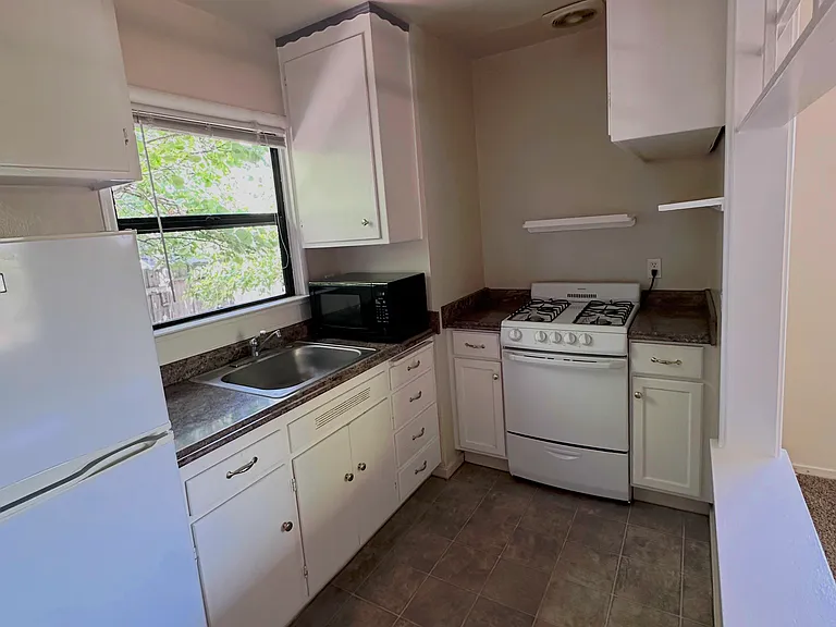Kitchenette with the range (gas) to the back middle; sink to the left and the refrigerator to the far left