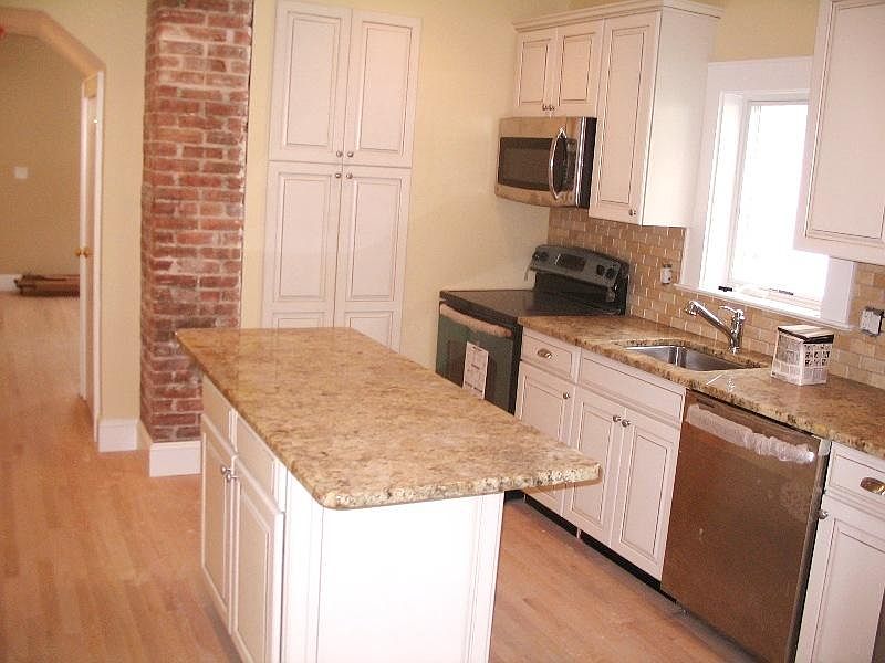 Granite Counters, Stainless Steel Appliances, Exposed Brick Wall, Plenty of Cabinetry for Storage.