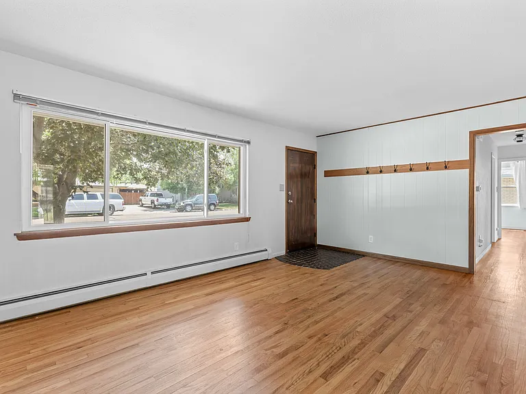 Thoughtful details include convenient wall hooks for coats and pet leashes, with the hallway leading to all three bedrooms and two full bathrooms.