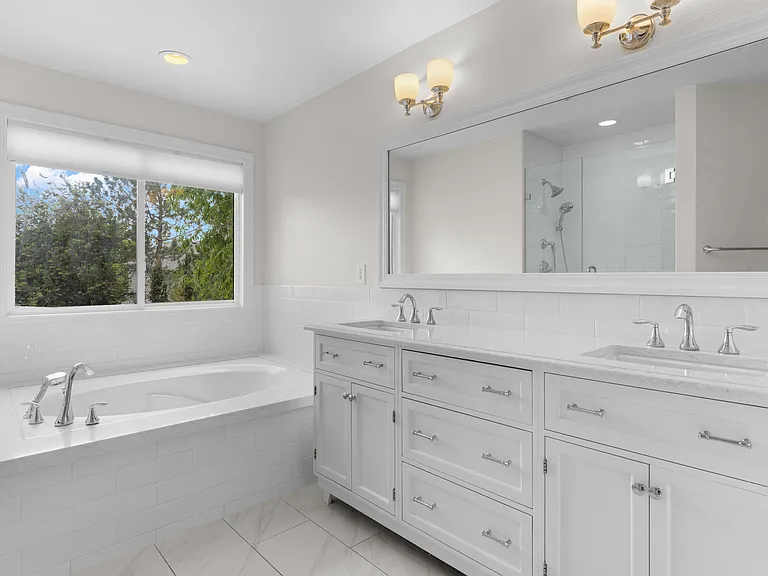 The spacious attached five-piece ensuite features dual vanities, a large soaking tub, and a functional layout designed for comfort and convenience.