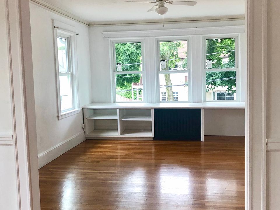 Large, sunny living room - The custom built-in features storage, a radiator cover, and a desk with power for a computer. It is easily removable.