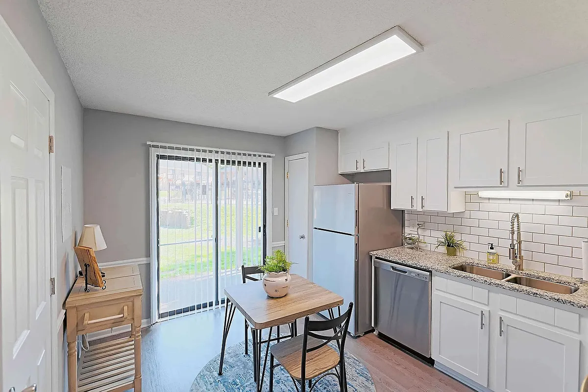 Bright eat-in kitchen with modern finishes, stainless steel appliances, and private patio access - Lindsey Manor