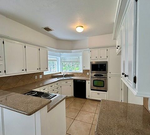 There are many kitchen cabinets, granite counters, and a new microwave. The adjoining wet bar/coffee bar is not shown.