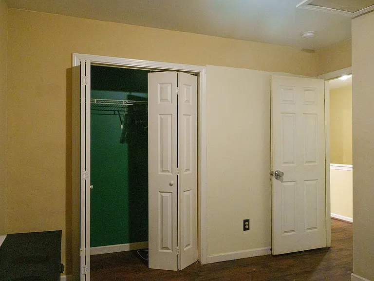 Bedroom area with a reach-in closet featuring wire shelving and convenient access to the hallway.