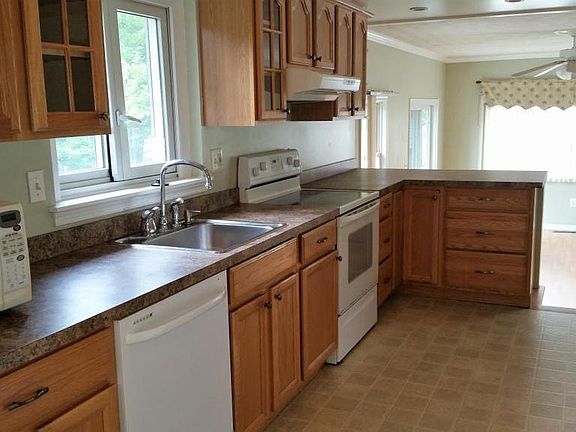 Galley-style kitchen. Oak wood cabinets on both sides. Flat-top electric stove with oven.