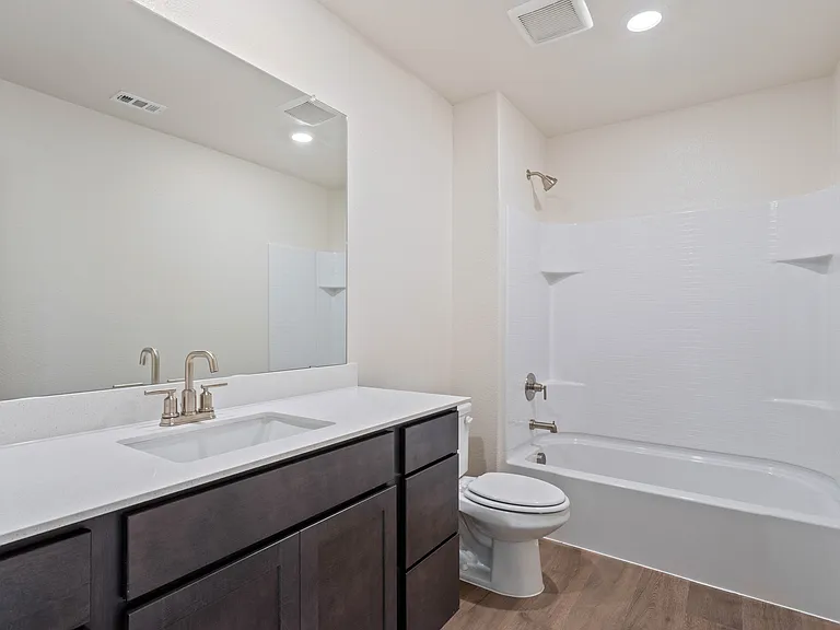 The secondary bathroom has a large vanity space and a shower-tub combo.