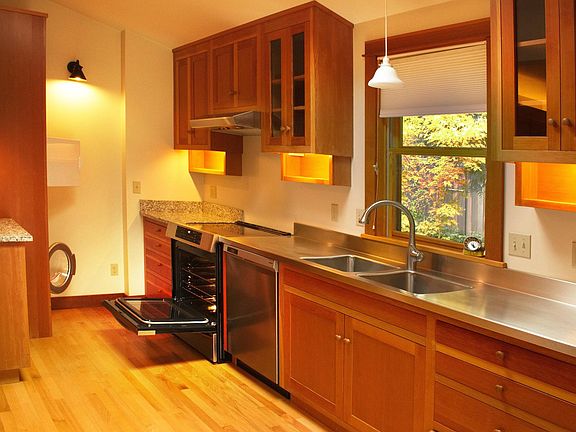 Washer and dryer in the corner, induction cooktop, electric oven, lighted cupboards, and skylight (above, not visible in this photo)