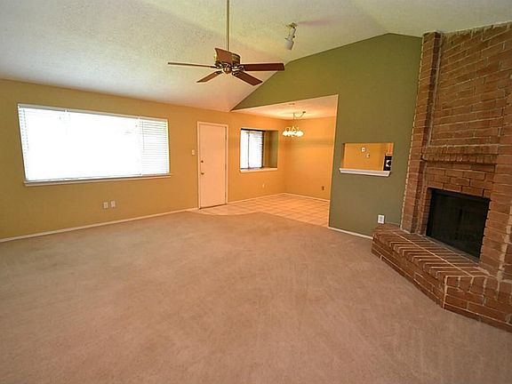 Spacious family room featuring raised coffered ceilings, ceiling fan and a wood burning corner firep