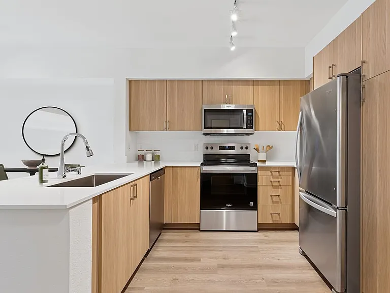 Renovated Package II with oak cabinetry, beige quartz countertops, white subway tile backsplash, stainless steel appliances, and hard surface flooring
