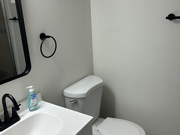 Efficient bathroom with a single-sink vanity, matte black fixtures, and easy-clean flooring for low-maintenance living.