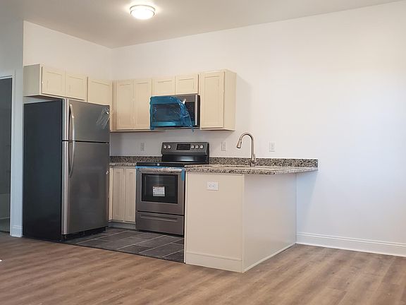 Kitchen with extended granite counter top for bar seating; there is a dishwasher; tile floor Main living area and bedroom have rigid core vinyl plank flooring