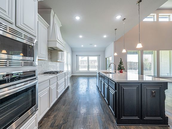 Kitchen featuring tasteful backsplash, a center island with sink, dark hardwood / wood-style flooring, and sink
