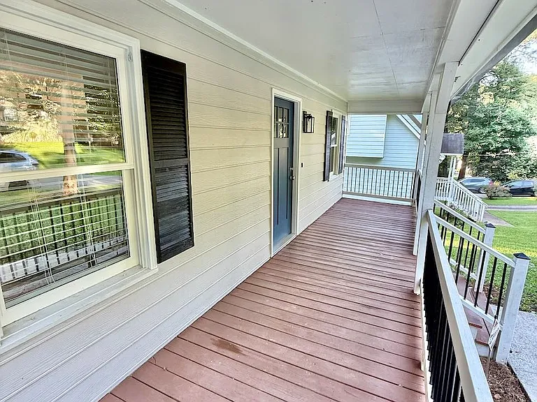 Welcoming front porch_ - spacious covered deck and sturdy railings offer all-weather comfort - perfect for morning coffee or evening chats while enjoying the lush yard.