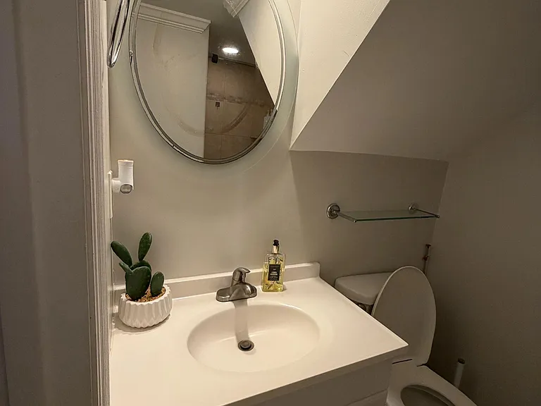 Compact half-bath with a vanity sink, framed mirror, and convenient toilet layout for everyday use.