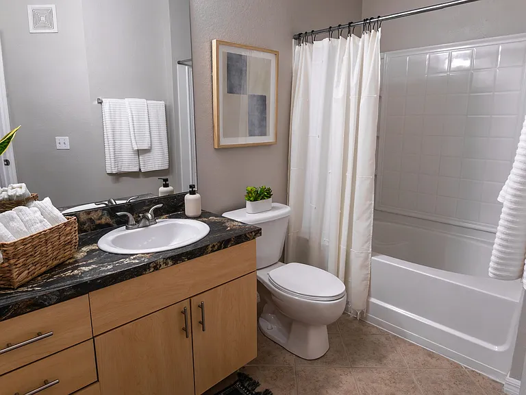 Enjoy a beautifully designed bathroom featuring modern finishes, a large mirror, and sleek countertops.