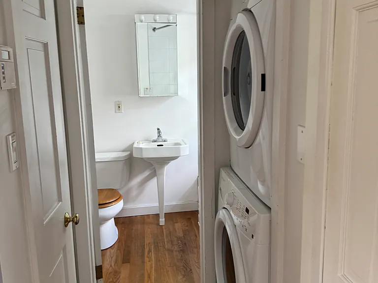 Hallway to bathroom with washer and dryer on right and linen closet on left.