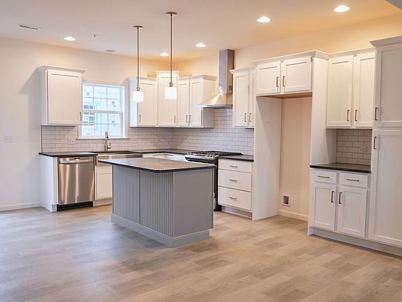 All brand new stainless steel appliances including refrigerator (not shown), dishwasher, and gas range with vented hood.