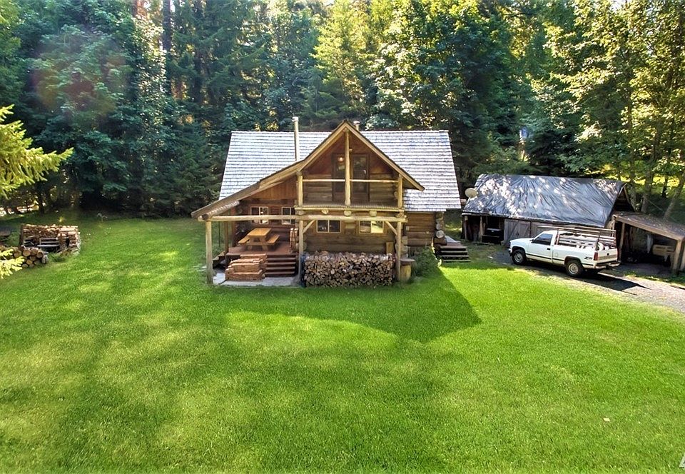 Straight on view of amazing log cabin built with local cedar logs. Deck off master bedroom up and off kitchen on the lower left. Far left has fire pit, hot tub & river flowing by!