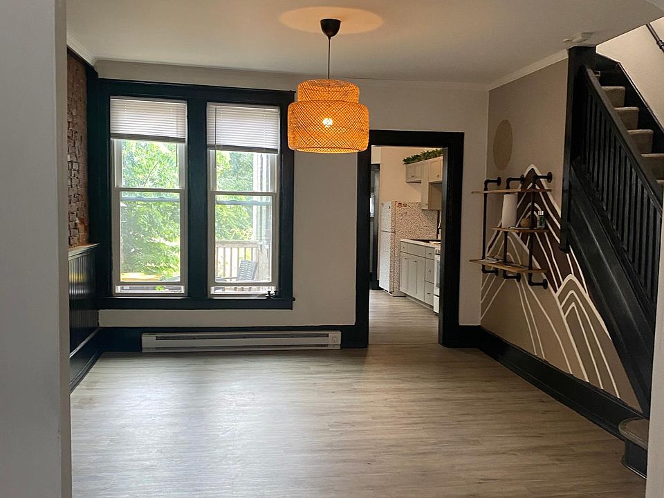 View of dining room with custom light and hand painted mural and shelving. Exposed brick throughout living room and dining room and two gorgeous extra tall windows for natural light