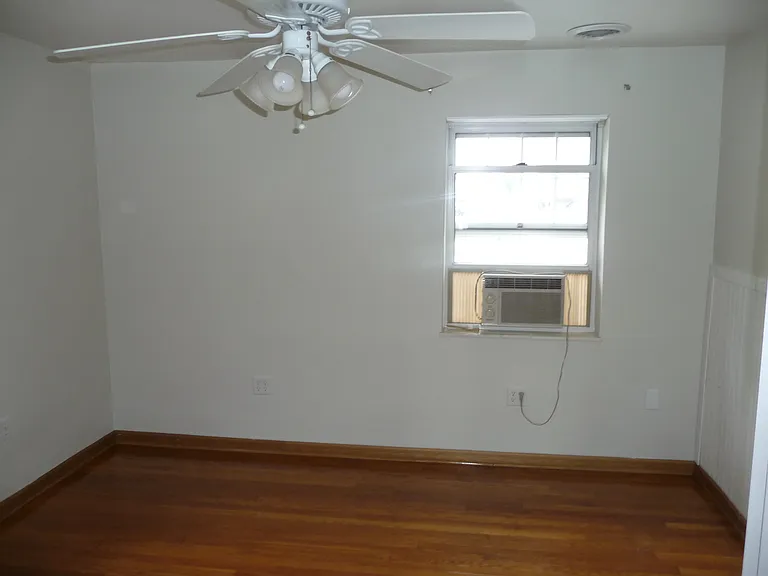Side yard window, in the bedroom. Oak hardwood floor and large white ceiling fan for your comfort.