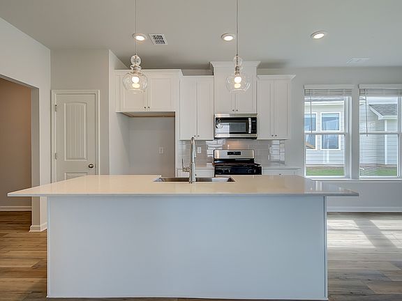 Modern kitchen in new construction home with large island, quartz countertops, and pendant lighting.