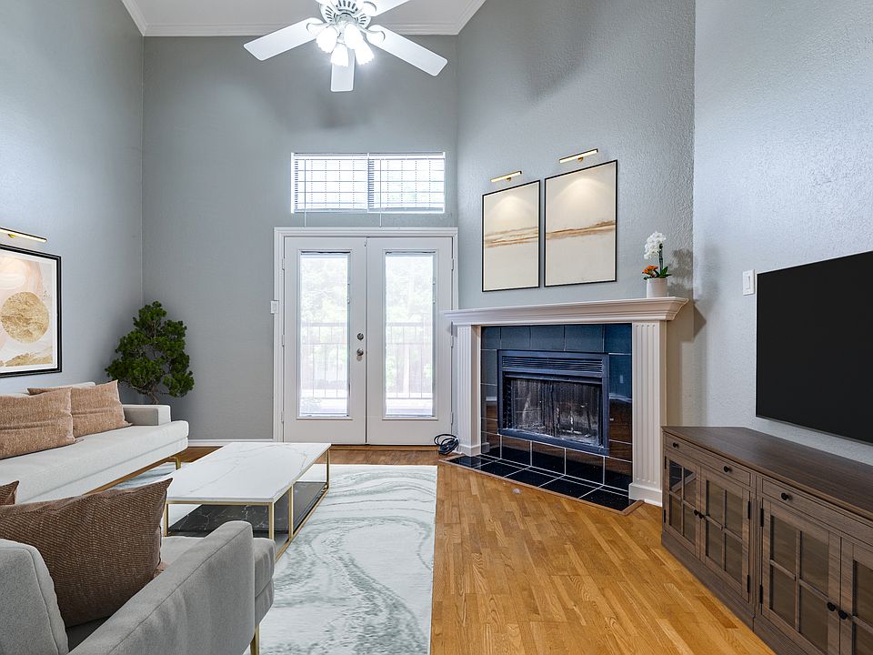 Virtually staged living area with hardwood floors, WBFP, french doors to balcony, high ceilings, and fan.