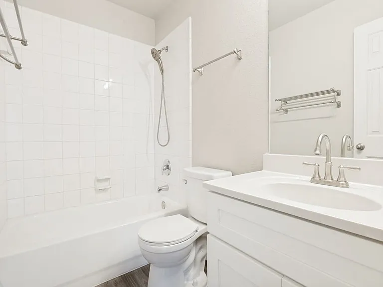 Full bathroom with bath shower combo in neutral colors.