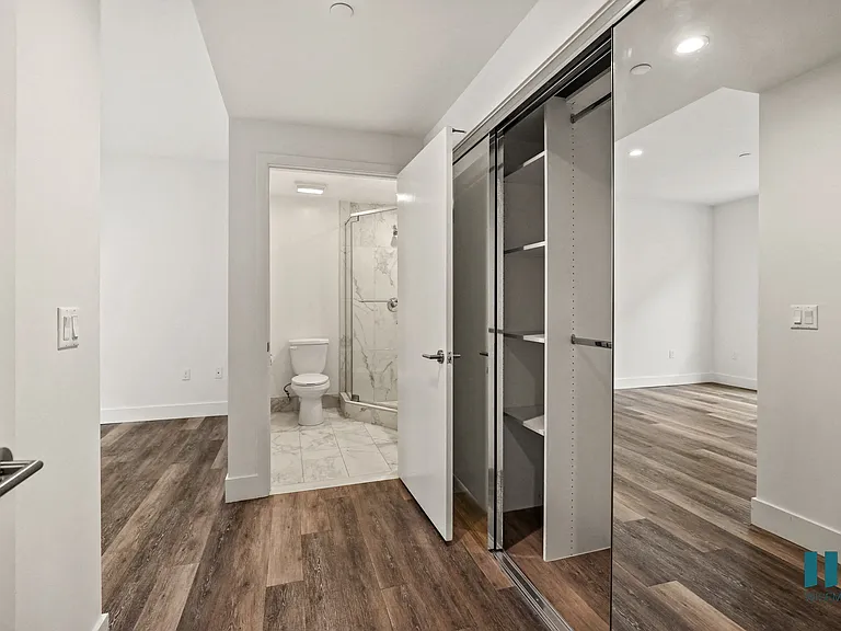 Bedroom with Large-Size Mirrored Closet with Built-In Shelving and Bathroom